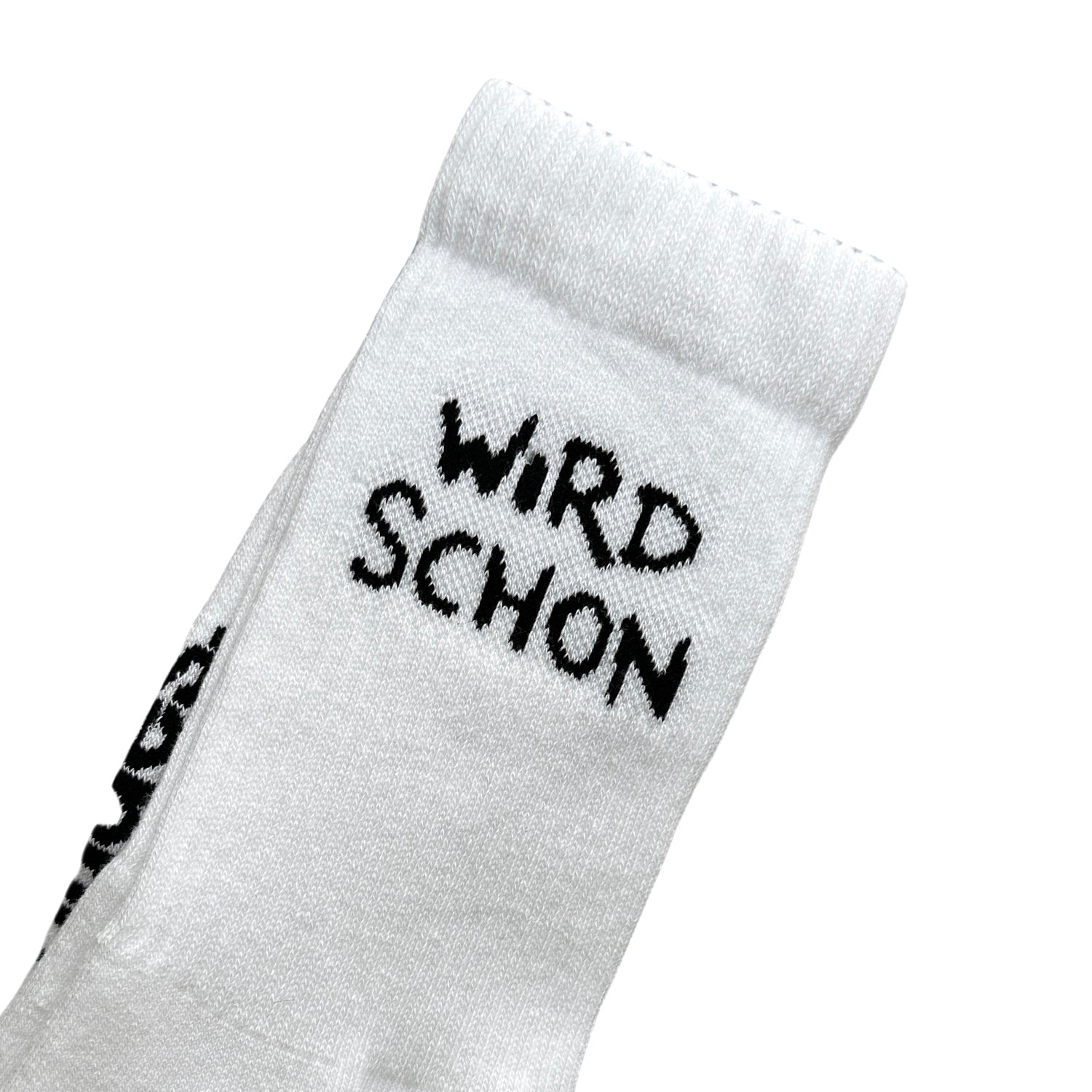 Detailaufnahme des oberen Schaftbereichs eines weißen Socks mit schwarzem Schriftzug „WIRD SCHON“ in handschriftlich anmutender Typografie. Deutlich sichtbare Rippenstruktur und feine Maschen.
